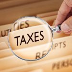 Magnifying glass over a folder labeled Taxes.