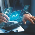 Calculator and laptop with digital tax symbols.
